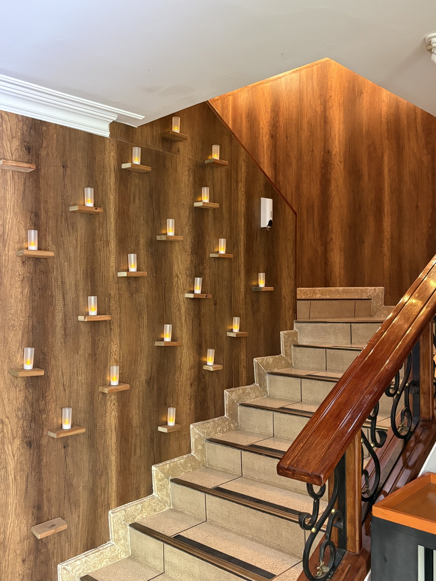 Muro de velas junto a la escalera de madera